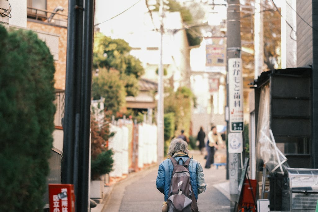 A person with a backpack strolls through a quaint street in Japan, capturing urban life.