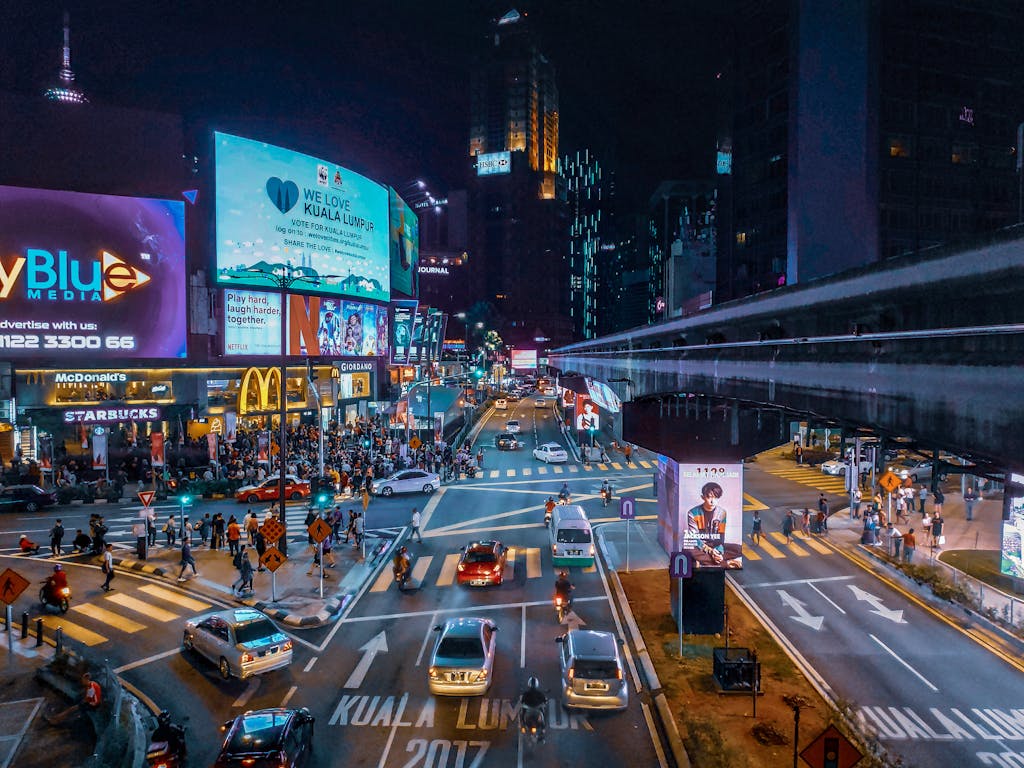 Bustling nighttime scene in Kuala Lumpur with illuminated streets and lively pedestrian traffic.