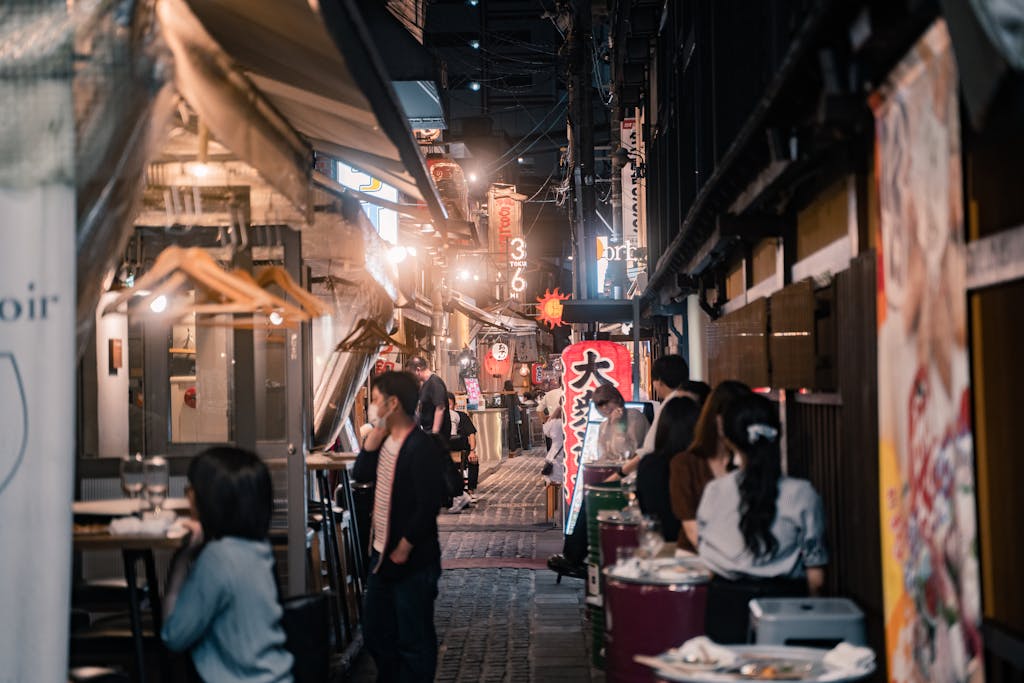 Explore the lively atmosphere of Osaka's alleyways with bustling crowds and inviting eateries.