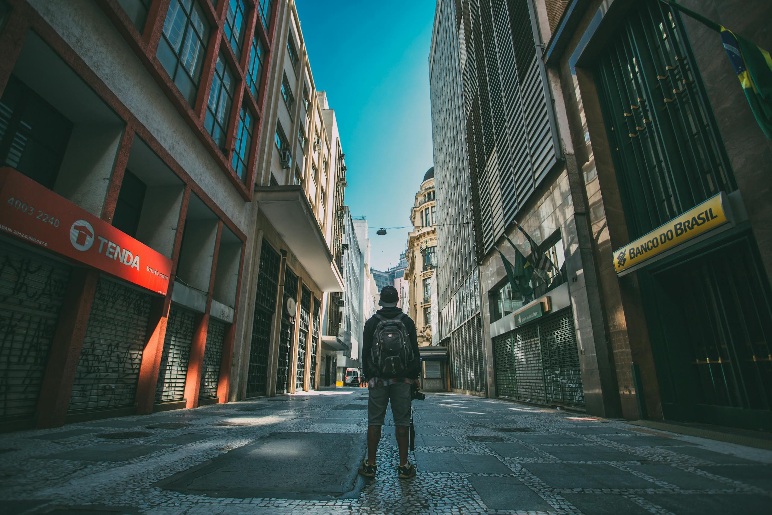 Man exploring São Paulo streets, vibrant urban atmosphere with towering buildings.